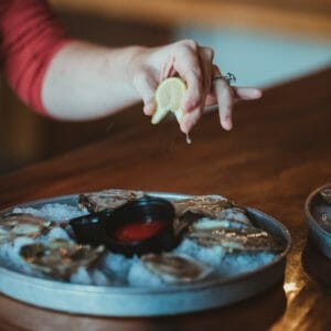 Squeezing lemon over oysters