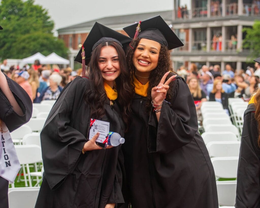 University of Lynchburg graduates, two girls out on the field in their caps and gowns