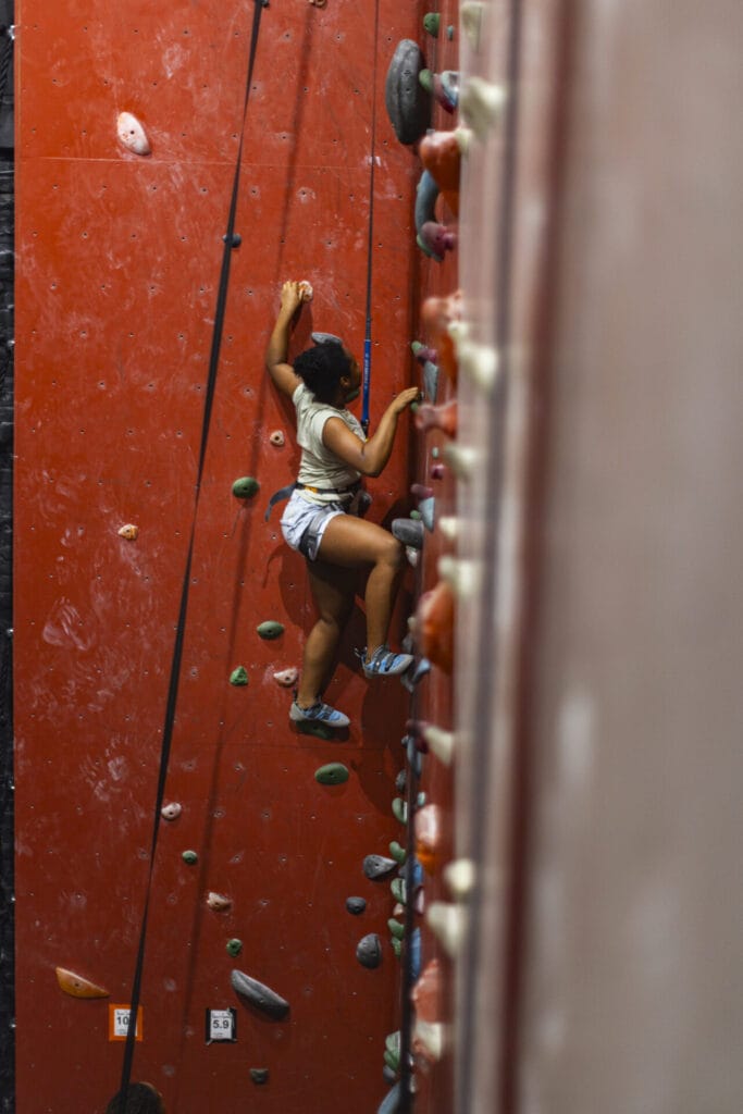 A woman rock climbing at Rise Up Climbing