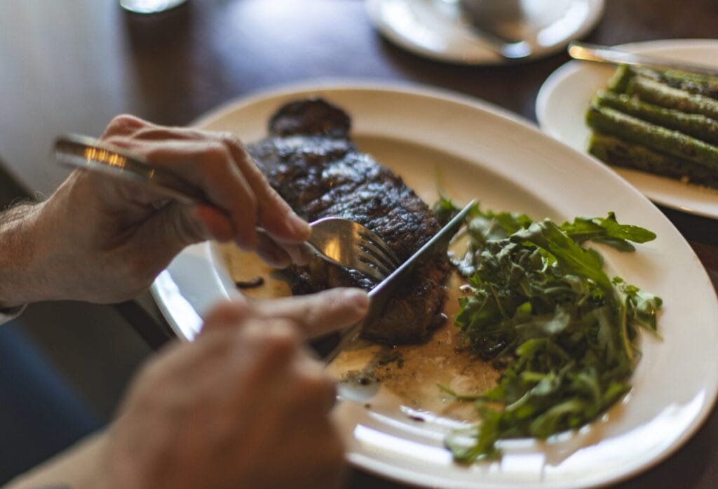 Photo of hands cutting into a steak at William & Henry Steakhouse