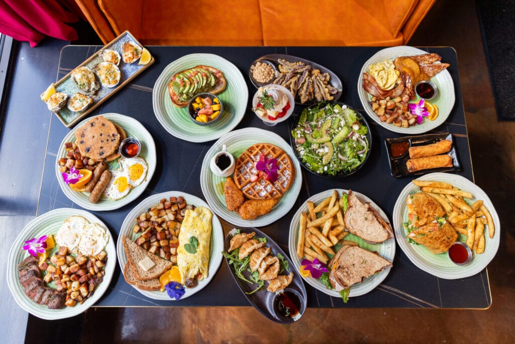 Interior table at Tiger Sun filled with plates of food; breakfast, brunch, lunch, and small plates