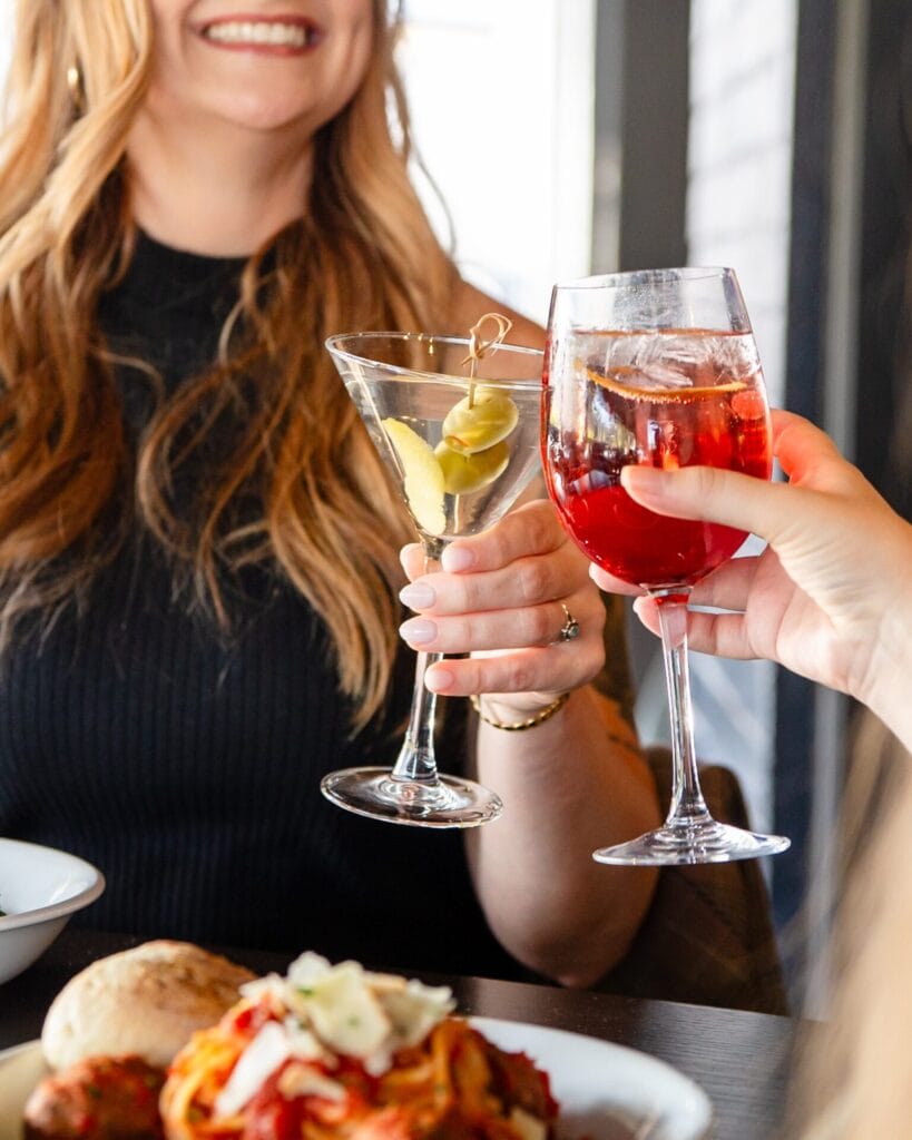 Two people cheers-ing cocktail drinks