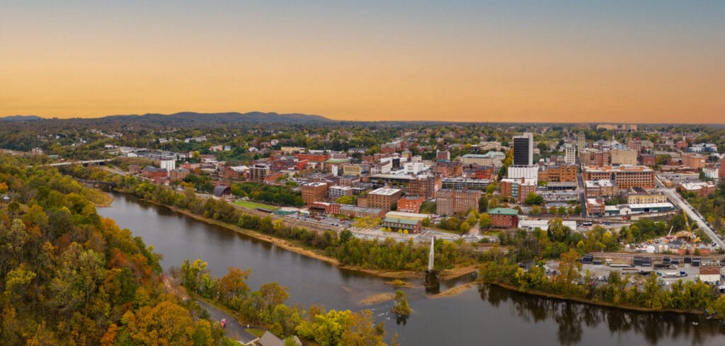 Drone and aerial view of Downtown Lynchburg surrounded by fall colors of orange, yellow, red, and green with the Blue Ridge Mountains in the distance